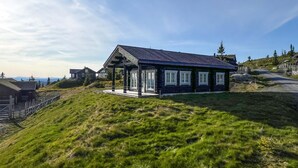 A modern house with a sloped roof, large windows, and a porch. - Nice home in Sjusjøen with house a mountain view (Sjusjøen)
