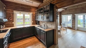 A kitchen with wooden cabinetry, a central island, and a view of the outdoors. - Nice home in Sjusjøen with house a mountain view (Sjusjøen)