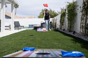 A backyard with a pool, a lounge chair, and a table with a flag.