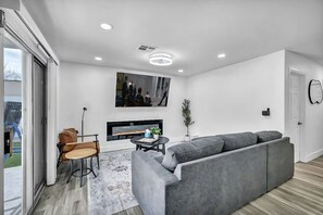 A modern living room with a grey sectional sofa, a small round table, and a fireplace.