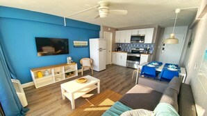 A compact living space with a kitchenette, a dining area, and a seating area with a sofa and a coffee table.