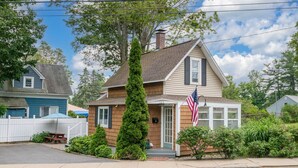 A two-story house with a front porch, a mailbox, and an American flag. - Adorable Seaside Cottage (Old Orchard Beach)