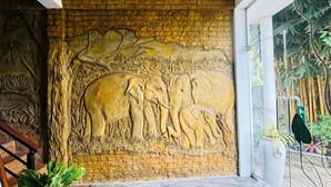 A reception area with a stone wall featuring a relief sculpture of elephants and a staircase with a 'WELCOME' sign. - Green Path  (Gampaha)