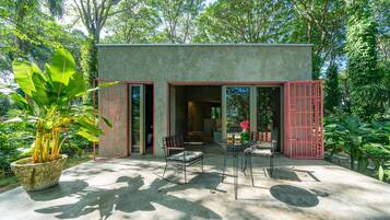 Uma casa moderna com fachada de concreto, grandes janelas e um espaço de varanda com mesa e cadeiras.