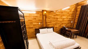 Een hotelkamer met een houten wand, een bed, een bureau en een stoel.
