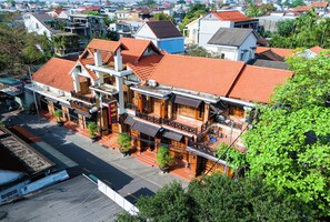 Un bâtiment traditionnel à plusieurs étages, doté d’un toit recouvert de tuiles rouges, de nombreux balcons et d’une entrée au niveau de la rue.