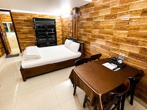 A hotel room with a bed, a wooden wardrobe, a table with chairs, and a tiled floor. - Pho Thien Duong Homestay (Hue)