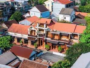 Un bâtiment traditionnel à plusieurs étages, doté d’un toit recouvert de tuiles rouges, de nombreux balcons et d’une entrée centrale.
