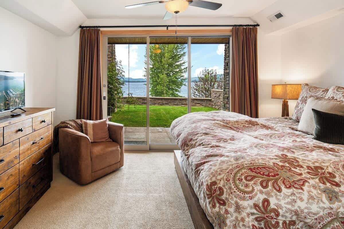 Ein Schlafzimmer mit einem großen Bett, einem Fernseher, einer Couch und Blick ins Freie.