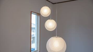 A room with a large window, three spherical hanging lights, and a framed picture on the wall.