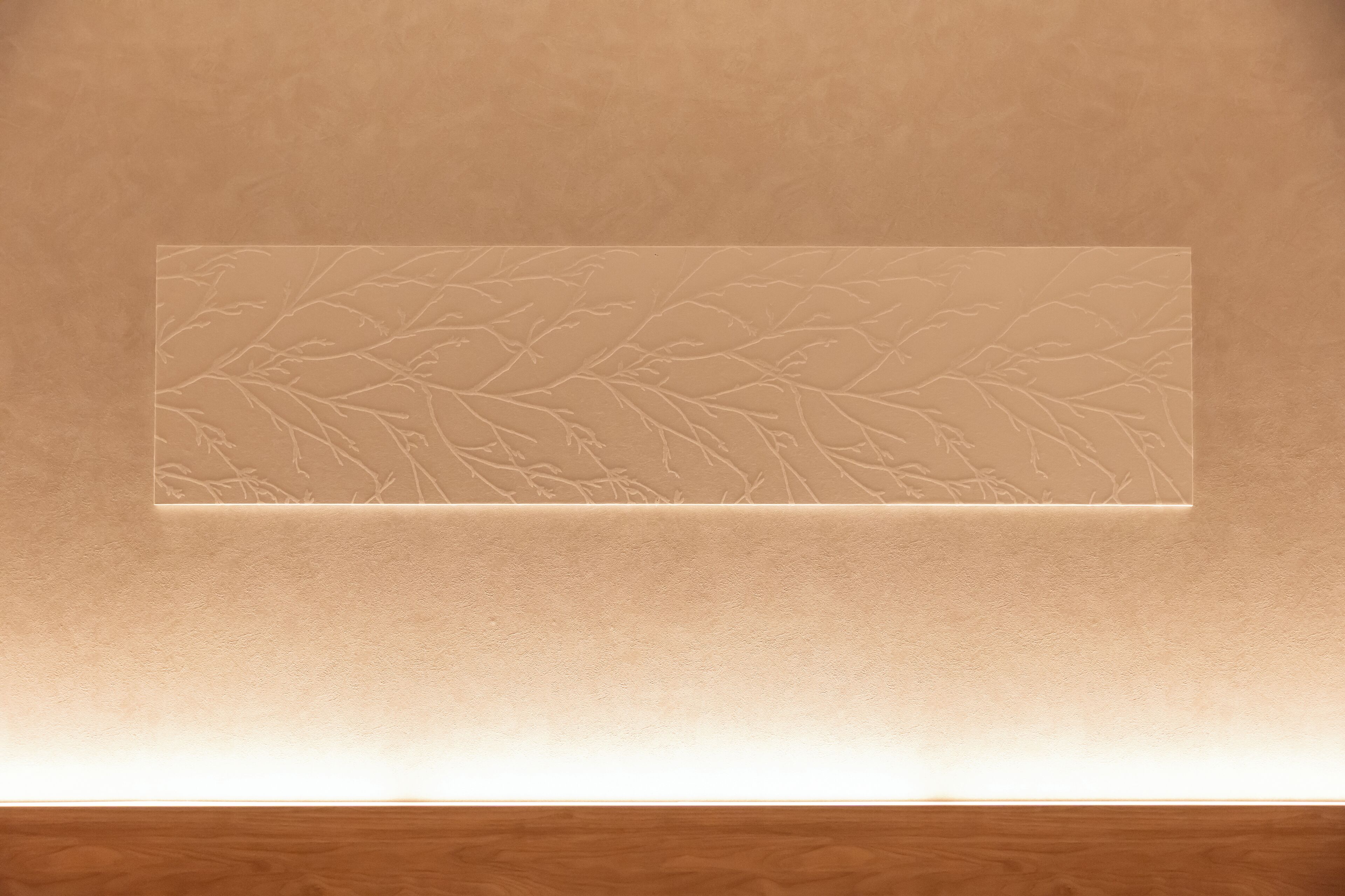 A textured wall with a recessed panel displaying a leaf pattern.