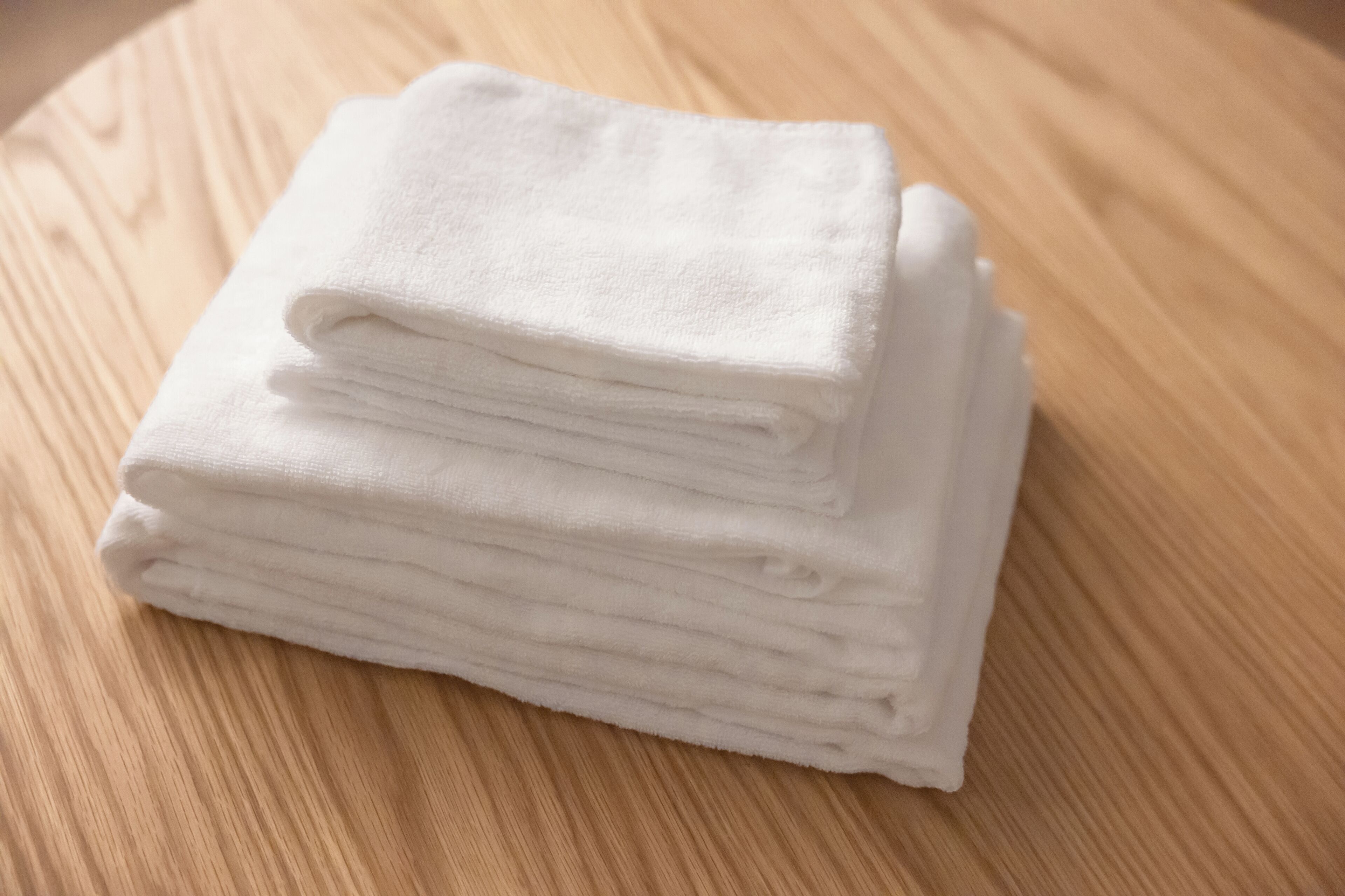 A stack of white towels on a wooden surface.