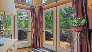A room with a large window, a door, a small table, a lamp, and a potted plant. - 3BR cabin w/ hot tub & outdoor deck (Mount Jackson)