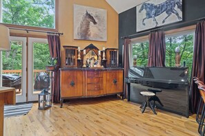 A spacious living room with a large wooden cabinet, a piano, and a view of the outdoors.