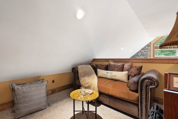 A cozy room with a brown leather sofa, a small round table with a glass, and a pillow with the word "HAPPY".