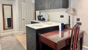 A modern kitchen with dark cabinets, a white countertop, and a wooden dining table.