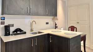 A kitchen with dark cabinets, a countertop, a sink, and a coffee maker.