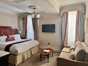 A hotel room with a bed, a sofa, a TV, and a chandelier. - New Studio Flat with AC, Marylebone (Greater London)