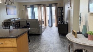 A spacious living area with a kitchen, dining area, and a view of the outdoors through large windows.