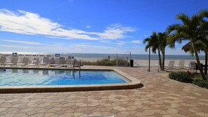 A swimming pool with lounge chairs and a view of the ocean.