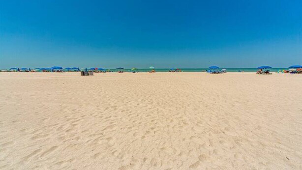 A wide sandy beach with a clear blue sky.