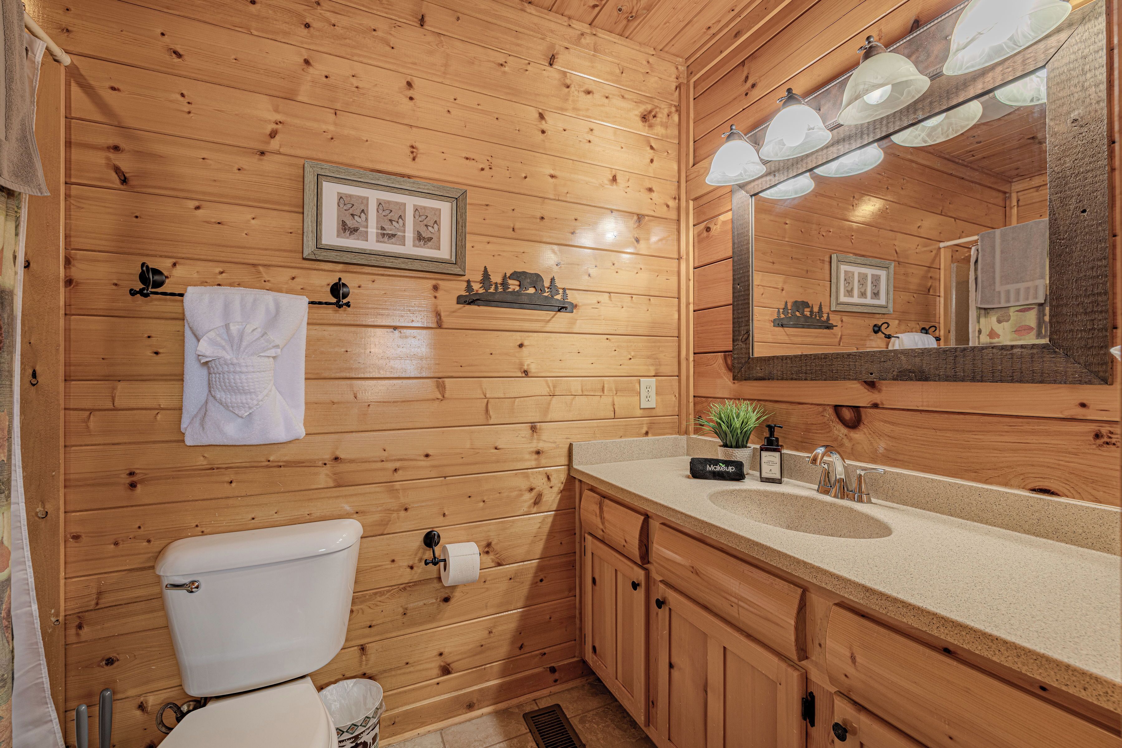 Ein Badezimmer einer Holzhütte mit Toilette, Waschbecken und Spiegel.