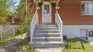 A two-story brick house with a white front door, a small porch with white railings, and a number '366' on the wall.