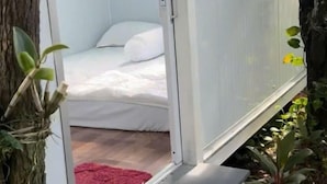 Una habitación con cama, un tapete rojo y una ventana con vistas al verdor.