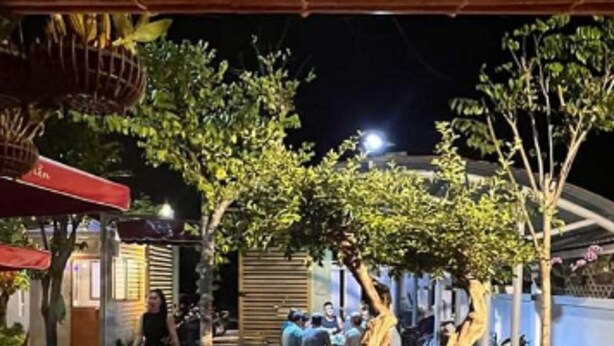 Un espacio al aire libre con plantas en macetas, una zona de estar techada y una persona caminando.