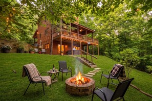 Une cabane en rondins dotée d’une terrasse, de coins salon extérieurs et d’un foyer.