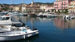 Un port de plaisance avec des bateaux amarrés, entouré de bâtiments aux couleurs vives et avec une colline en arrière-plan.