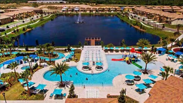 A resort with a central swimming pool, multiple smaller pools, and a large lake with a fountain.