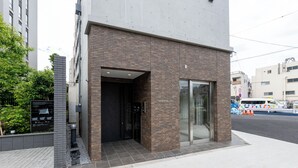A modern building with a brick facade, a glass entrance, and a small outdoor seating area with plants. - Less than 10 minutes from each of Shibuya, Shinjuku and Harajuku/ Central location/ New construction/ Max. 6 people (渋谷区)