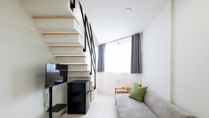 A modern living room with a staircase, a flat-screen TV, a sofa, and a small table with a remote control. - Less than 10 minutes from each of Shibuya, Shinjuku and Harajuku/ Central location/ New construction/ Max. 6 people (渋谷区)