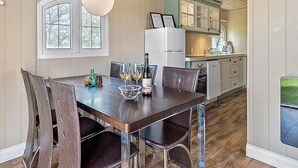 Un comedor con una mesa de madera, sillas oscuras y una lámpara colgante.