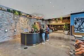Un espace d’accueil avec un mur en briques, un comptoir d’accueil incurvé et un coin salon doté d’un grand écran diffusant des œuvres d’art abstrait.