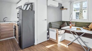 A compact kitchen with a built-in refrigerator, a wooden countertop, and a window with a view of the outside. - 9 Person Holiday Park Home in Otterup (Otterup)