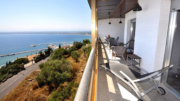 Un balcon avec vue sur la mer, une table avec des chaises et une rambarde.