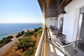 Een balkon met uitzicht op zee, een tafel met stoelen en een hekwerk.