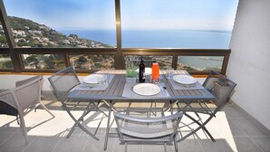 Un coin repas avec une table dressée pour quatre personnes, offrant une vue sur la côte.