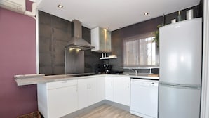 Une cuisine moderne avec des armoires blanches, une hotte de cuisinière en acier inoxydable et un réfrigérateur blanc.