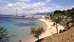 Une plage côtière aux eaux limpides, avec un rivage sablonneux et quelques bateaux amarrés près du rivage.