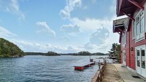 A waterfront property with a dock extending into a lake, surrounded by trees and a clear sky. - Beautiful home in Lepsøy with WiFi (Lepsøy)