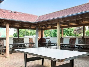 An outdoor pavilion with a ping pong table, picnic tables, and a stone wall. - 9 Person Holiday Park Home in Otterup (Otterup)