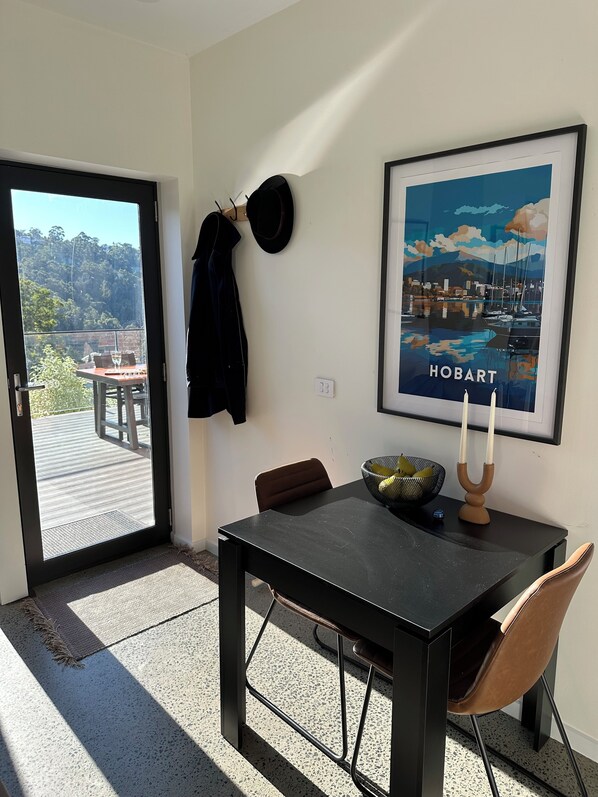 A room with a black table, a brown chair, a framed picture of Hobart, and a hat hanging on the wall. - Modern SoHo Pad (South Hobart)