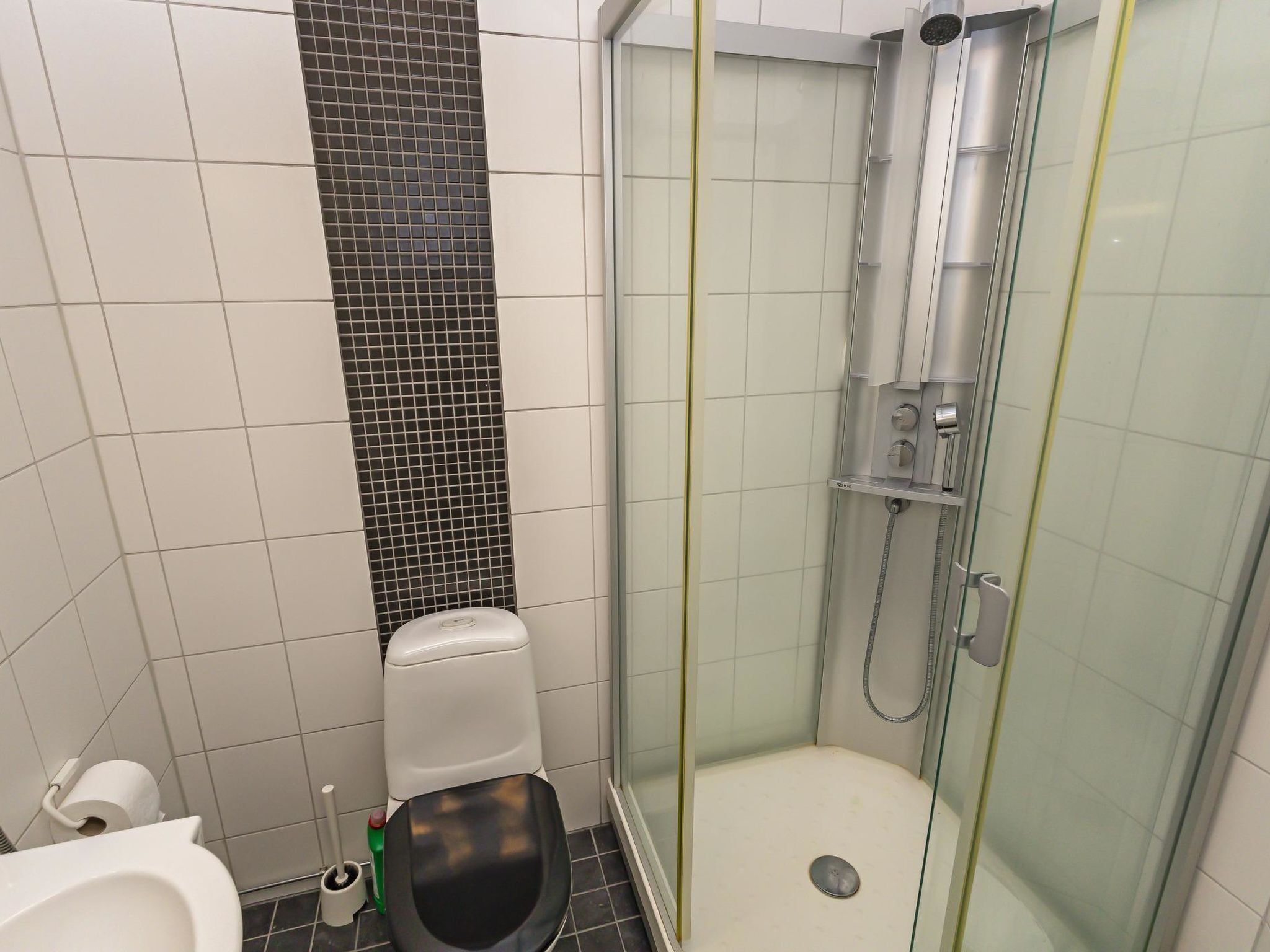 Et lille, moderne badeværelse med toilet, bidet og en brusekabine med glasvægge.