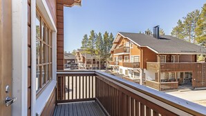 A wooden balcony with a view of a multi-story building with balconies and a ski lift in the background. - Levin alppi 3 b 7 by Interhome (Kittilä)