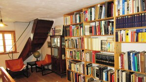Une bibliothèque avec des étagères, un escalier en colimaçon et un globe terrestre.