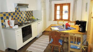 Une cuisine de taille réduite avec des meubles blancs, une cuisinière et une table à manger avec des chaises.