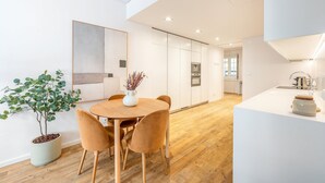 Una cocina moderna con armarios blancos, una mesa de comedor de madera con sillas y una planta en maceta.